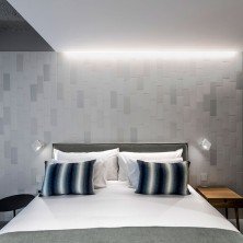 Lámparas Alpha 7942 de Vibia instaladas a ambos lados de la cama en habitación de hotel