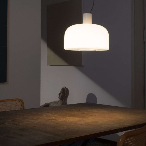 Lámpara Bellhop Glass S1 de Flos suspendida sobre mesa de comedor con luz cálida encendida Lámpara Bellhop Glass S1 de Flos suspendida sobre mesa de comedor con luz cálida encendida