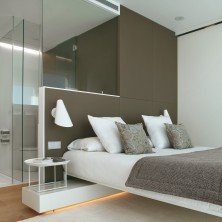 Aplique I.cono 0720 blanco con interruptor integrado instalado en cabecero de dormitorio contemporáneo.