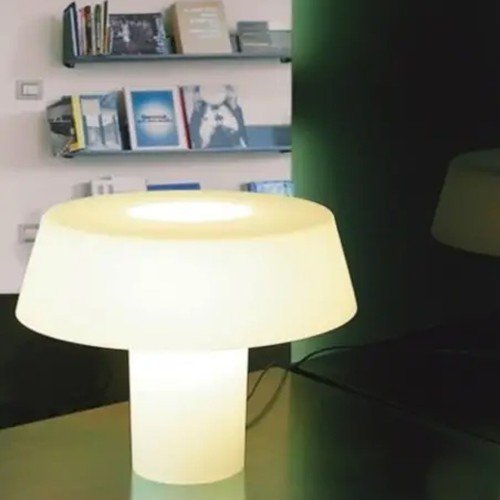 Amami de Artemide iluminando una estantería; lámpara de sobremesa decorativa en blanco opal Amami de Artemide iluminando una estantería; lámpara de sobremesa decorativa en blanco opal